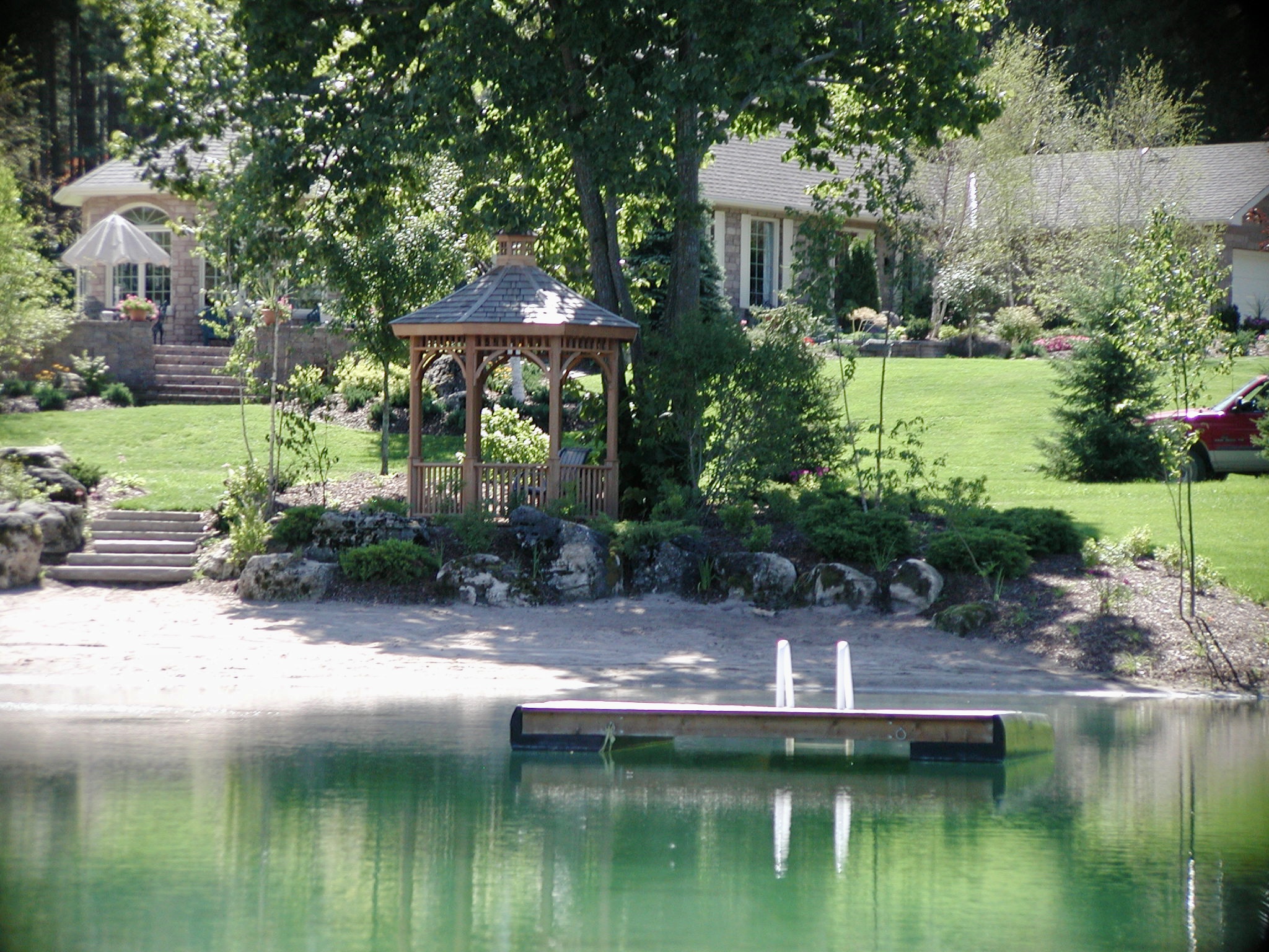 Shoreline planting and sandy pond edge in a completed Headwaters landscape project